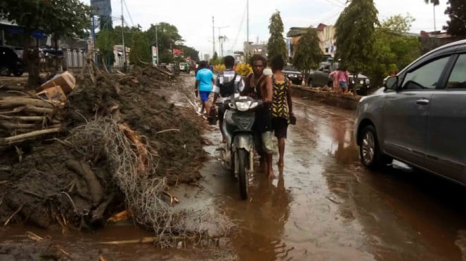 Warga mendorong motor melintasi sisa lumpur akibat banjir bandang di Sentani, Kabupaten Jayapura, Papua, Minggu, 17 Maret 2019. Warga mendorong motor melintasi sisa lumpur akibat banjir bandang di Sentani, Kabupaten Jayapura, Papua, Minggu, 17 Maret 2019.