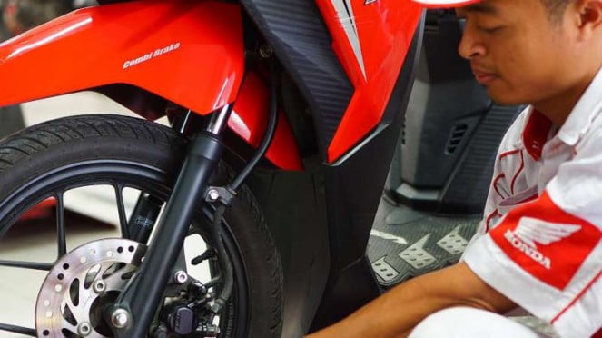 Teknisi mengecek rem sepeda motor Teknisi mengecek rem sepeda motor