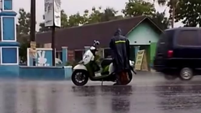 Pemotor mengenakan jas hujan Pemotor mengenakan jas hujan
